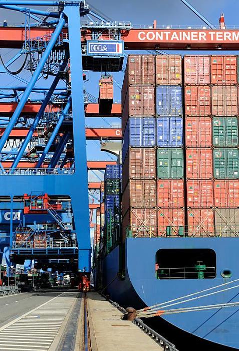 Hamburger Hafenfotografie - Bilder vom HHLA Containerterminal Altenwerder, Containerkatze 011_86_0140 ber die Containerbrcken wird die Ladung des Schiffs gelscht - hoch oben an der Katze des Auslegers hngt eine der vielen Metallboxen und wird an Land gebracht.