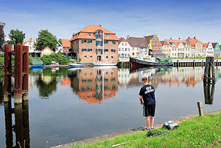 1504 Binnenhafen von Glckstadt an der Unterelbe - ein Angler steht am Kai - auf der gegenber liegenden Seite Wohnhuser und ein historischer Speicher.