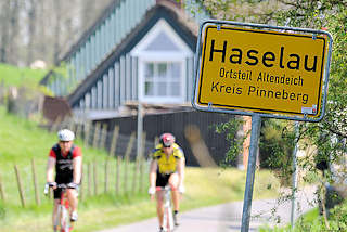 1147 Ortschild Haselau, Ortsteil Altendeich - Kreis Pinneberg; Radfahrer auf der Deichstrasse - Wohnhuser mit Reet gedeckt.