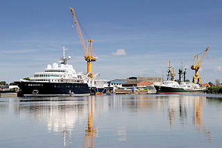 8747 Werftanlagen an der Str in Wewelsfleet - Schiffe liegen am Ausrstungskai - Werftkrne stehen am Ufer.